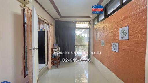 Bright living area with large windows and a mix of exposed brick and white walls.