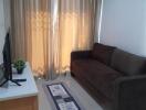 Living room with sofa, TV, and curtains