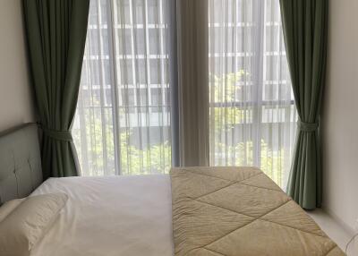 A modern bedroom with large windows and green curtains