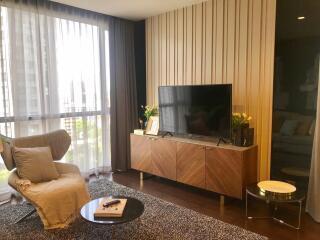 Modern living room with a large window, TV, armchair, and a coffee table