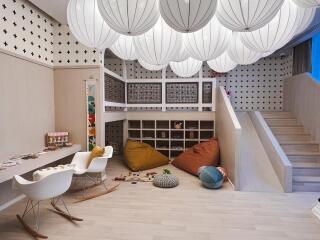 Well-lit and fun playroom with play mats, toys, bean bags, and unique ceiling decor.