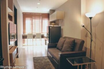 Living room with sofa, dining area, and natural light from windows