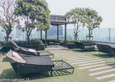 Rooftop terrace with lounge chairs, green space, and city views