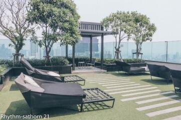 Rooftop terrace with lounge chairs, green space, and city views