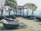 Rooftop terrace with lounge chairs, green space, and city views