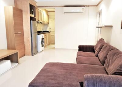 Living room with brown sofa and view of kitchen