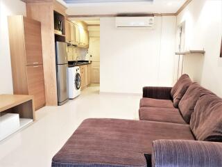 Living room with brown sofa and view of kitchen