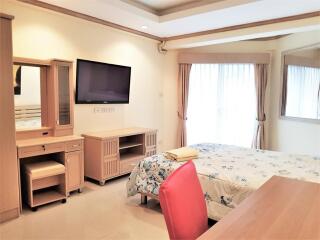 Well-lit bedroom with a TV, desk, and double bed