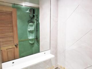 Modern bathroom with shower, large mirror, and tiled walls