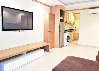 Modern living area with wall-mounted TV, kitchen, washing machine, and air conditioning