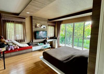 Modern bedroom with wooden flooring, large windows, and balcony view