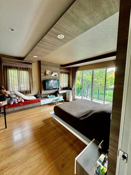 Modern bedroom with wooden flooring, large windows, and balcony view