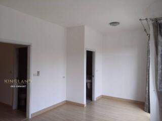 Bedroom with light wooden flooring, white walls, dual doorways, and a ceiling light fixture