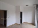 Bedroom with light wooden flooring, white walls, dual doorways, and a ceiling light fixture