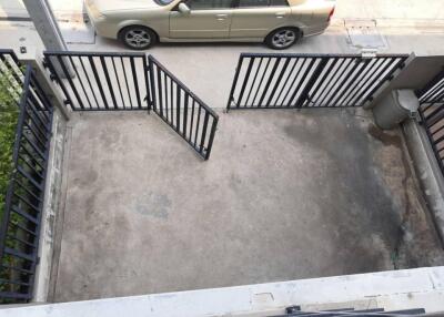 Outdoor parking area with black metal gate and beige car outside