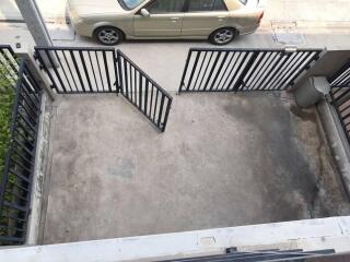 Outdoor parking area with black metal gate and beige car outside