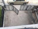 Outdoor parking area with black metal gate and beige car outside