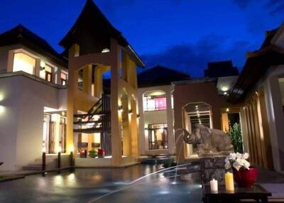 Exterior view of a luxurious outdoor area with a pool, traditional architecture, and a decorative elephant fountain