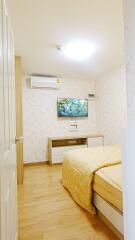 Modern bedroom with a bed, wall-mounted TV, air conditioner, and wooden flooring