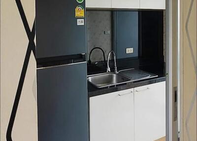 Compact kitchen with black countertops, stainless steel sink, and modern appliances