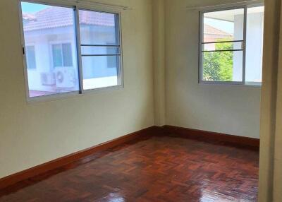 Empty bedroom with wooden floor and two windows