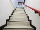 Staircase with a red handrail and beige steps