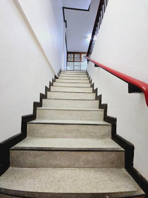 Staircase with a red handrail and beige steps