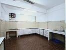 Spacious kitchen with brown tiled floor, white cabinets, and ceiling fan