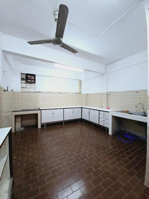 Spacious kitchen with brown tiled floor, white cabinets, and ceiling fan