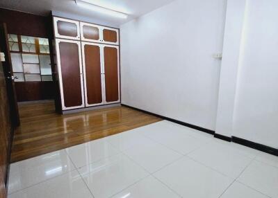 Spacious bedroom with built-in wooden wardrobes and tiled flooring