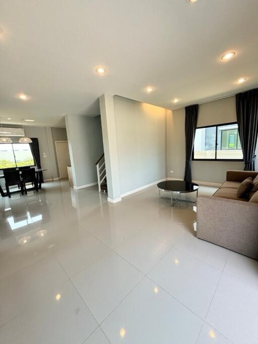 Spacious living room with tiled floors, large window, and dining area connected to an open staircase