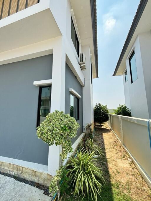 Side view of a modern white and grey building with vegetation