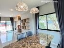 Marble dining table in a bright dining area with chandelier lighting and large windows