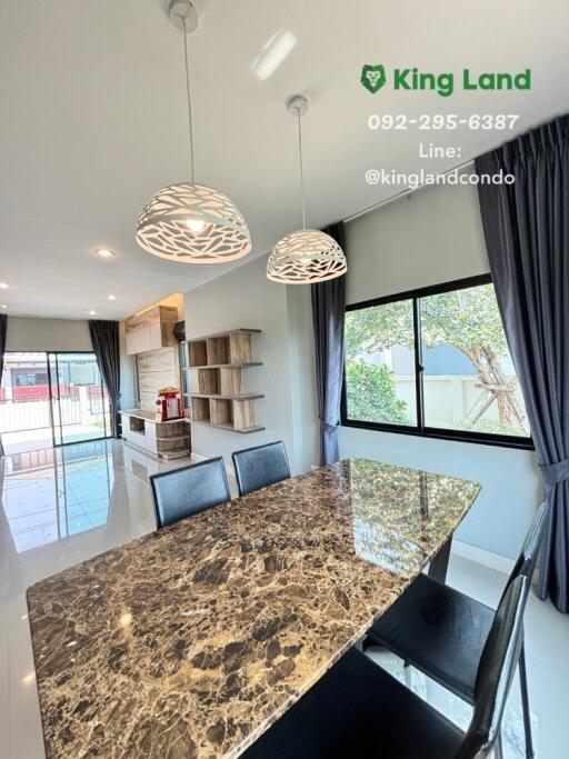 Marble dining table in a bright dining area with chandelier lighting and large windows