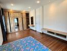 Spacious bedroom with wooden flooring, built-in wardrobe, and natural light