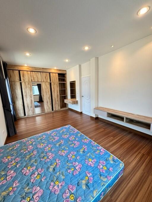 Spacious bedroom with wooden flooring, built-in wardrobe, and natural light