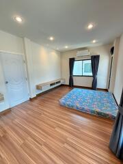 Spacious bedroom with wooden flooring and a window