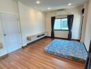 Spacious bedroom with wooden flooring and a window