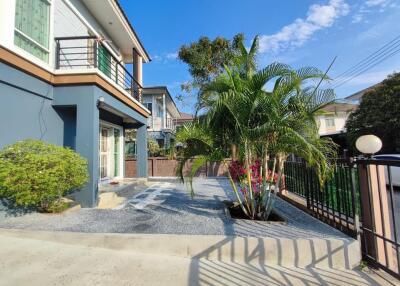 Front view of house with driveway, garden, and neighboring houses