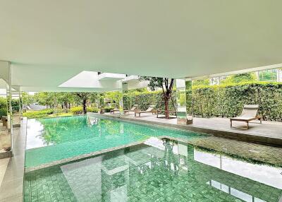 Indoor swimming pool with seating area and greenery view