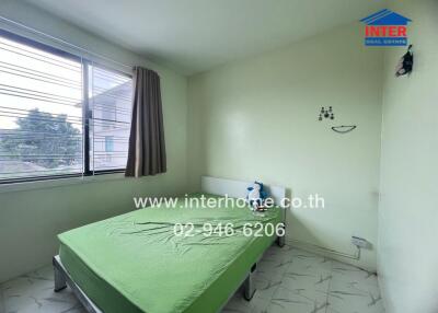 Bedroom with a green bedspread and a window with curtains