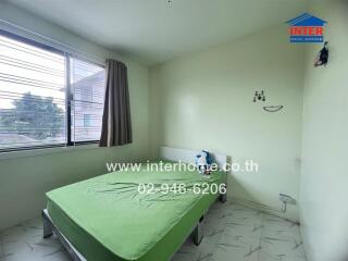 Bedroom with a green bedspread and a window with curtains