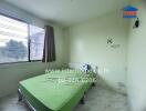 Bedroom with a green bedspread and a window with curtains