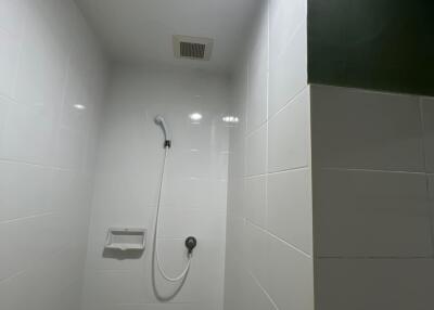 Modern bathroom shower area with white tiles and overhead lighting