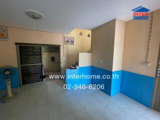 Living area with tiled floor, phone number displayed, and partition walls