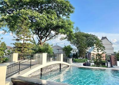 Outdoor swimming pool with a bridge and trees in the background