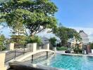 Outdoor swimming pool with a bridge and trees in the background