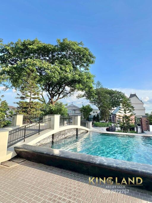 Outdoor swimming pool with a bridge and trees in the background