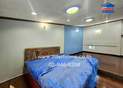 Bedroom with bed, blue blanket and wall-mounted lights