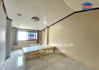 Bedroom with a large window, tiled floor, and stacked mattresses